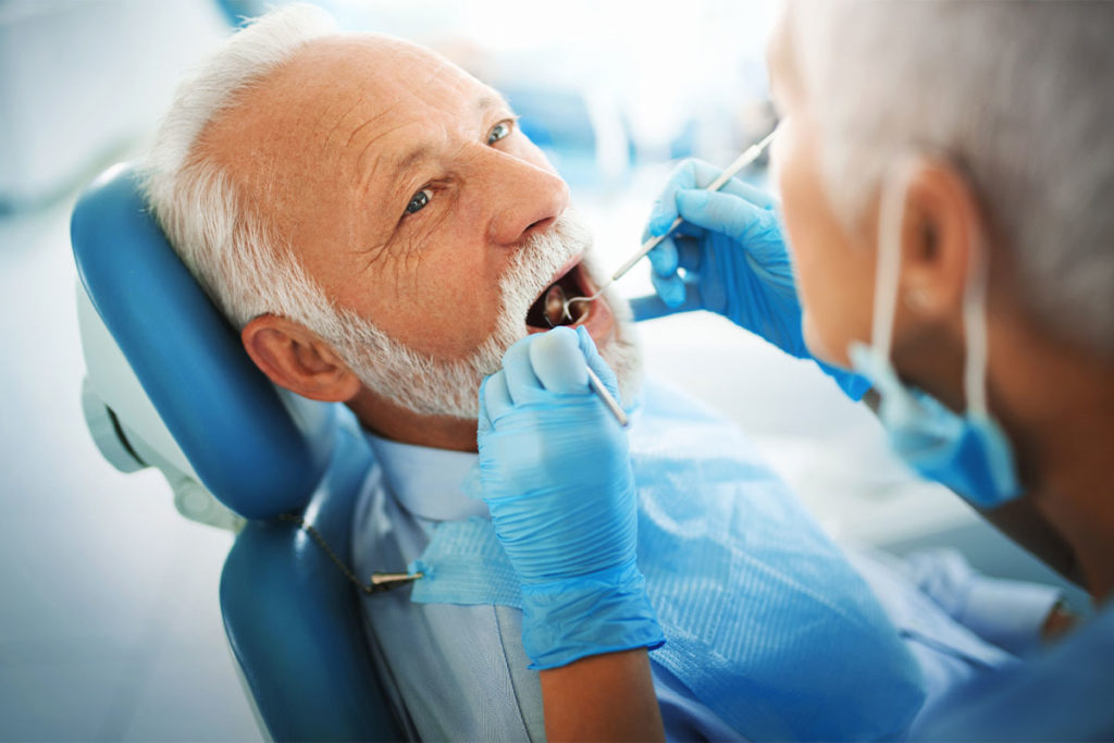 An older man happily receiving a dental exam prior to fillings in San Diego.